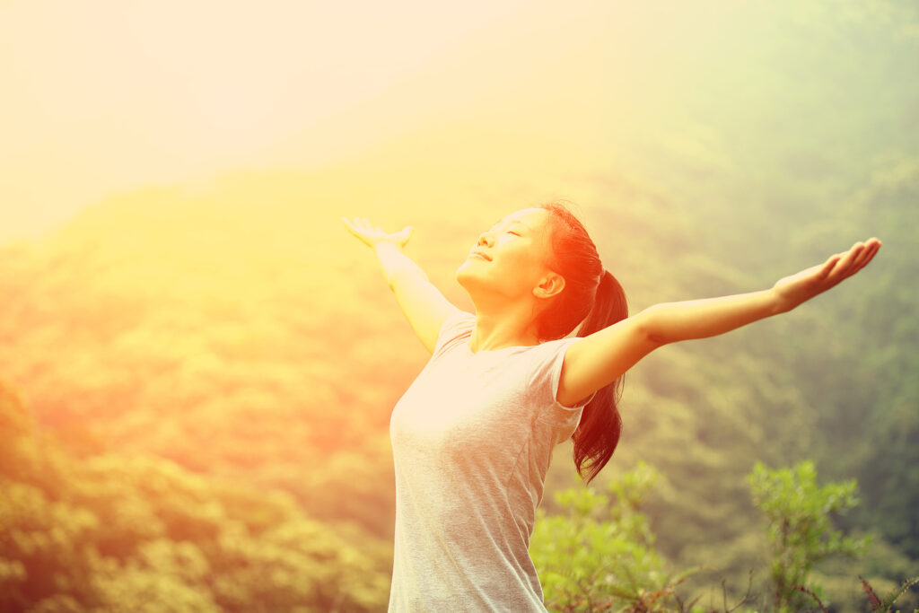 woman standing with arms wide open to the sun